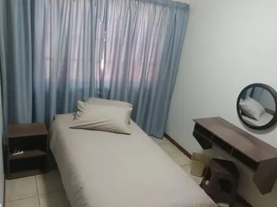 a bedroom with a bed and a mirror next to a window at Ebeneezer Self-Catering Guesthouse in the Lowveld in Sabie