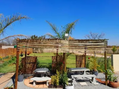 a wooden pergola with tables and benches in a yard at Mogale Royal Gardens in Polokwane