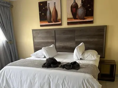 a bedroom with a white bed with vases on the wall at Mogale Royal Gardens in Polokwane