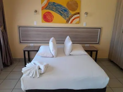 a white bed in a room with a painting on the wall at Mogale Royal Gardens in Polokwane