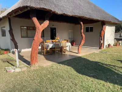 a house with a thatched roof with a table and chairs at Vanross Self Catering Accommodation in Thabazimbi