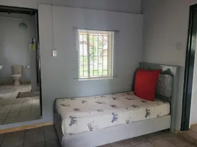 a bedroom with a bed with a red pillow at Vanross Self Catering Accommodation in Thabazimbi