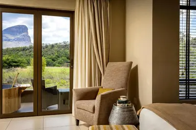 a bedroom with a chair and a window with a view at Sofala Lodge in Mokopane