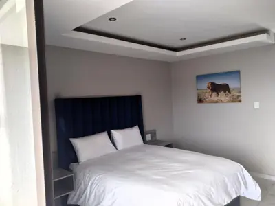 a bedroom with a white bed and a picture of a horse at Thomsons Lodge in Polokwane