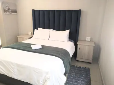 a bedroom with a large bed with a black headboard at Thomsons Lodge in Polokwane