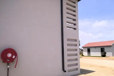 a white wall with a ladder on the side of a building at Thomsons Lodge in Polokwane