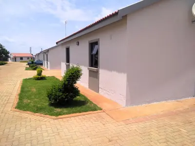 a white building with two bushes in front of it at Thomsons Lodge in Polokwane