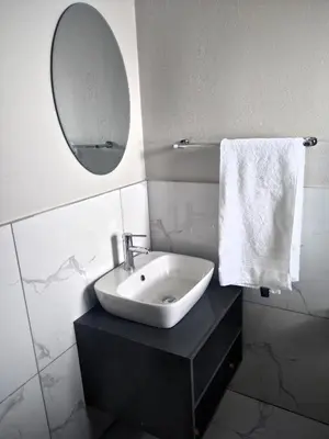 a white bathroom with a sink and a mirror at Thomsons Lodge in Polokwane