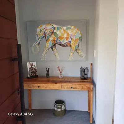 a wooden table with a mosaic elephant painting on the wall at Palahala in Marloth Park