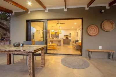 a dining room with a table and a living room at Palahala in Marloth Park