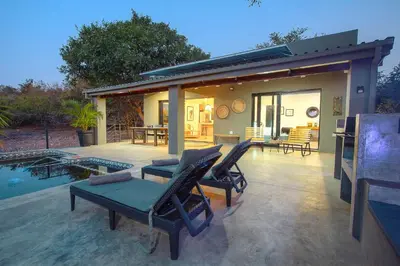 a patio with chairs and a pool and a house at Palahala in Marloth Park