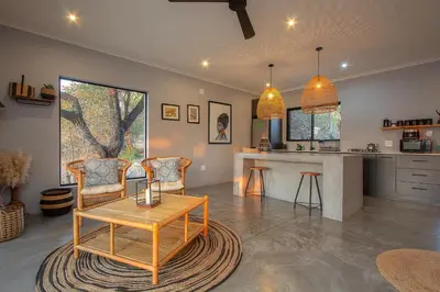 a living room with a table and chairs and a kitchen at Palahala in Marloth Park