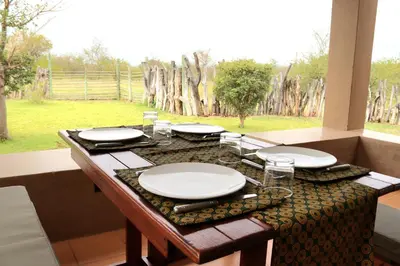a table with plates and glasses on top of it at iMbamuweti Cottage in Grietjie Nature Reserve