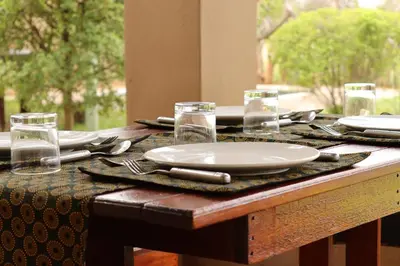a wooden table with a plate and utensils on it at iMbamuweti Cottage in Grietjie Nature Reserve