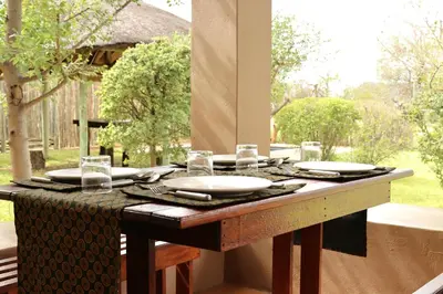 a table with plates and glasses on top of it at iMbamuweti Cottage in Grietjie Nature Reserve