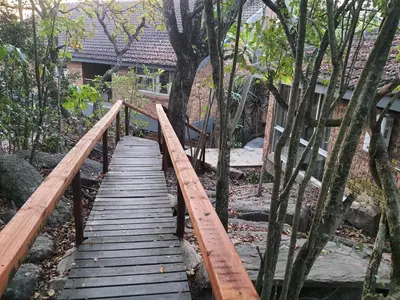 a wooden bridge in a garden with trees at Bikkurim Inn in Nelspruit