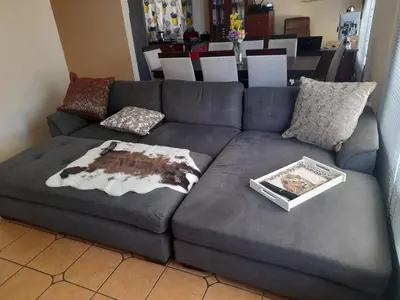 a grey couch with pillows and a book on it at Harambi in Nelspruit