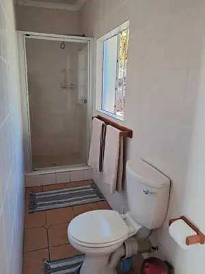 a bathroom with a toilet and a shower with towels at Harambi in Nelspruit