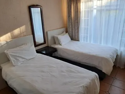 a hotel room with two beds and a window at Harambi in Nelspruit