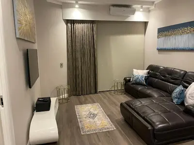 a living room with a leather couch and a tv at Menlyn Maine Unit 1421 in Pretoria