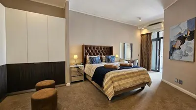 a bedroom with a large bed and two stools at Menlyn Maine Unit 1421 in Pretoria