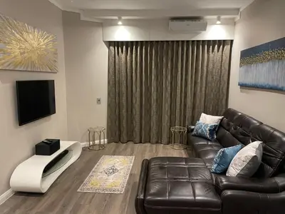a living room with a leather couch and a television at Menlyn Maine Unit 1421 in Pretoria