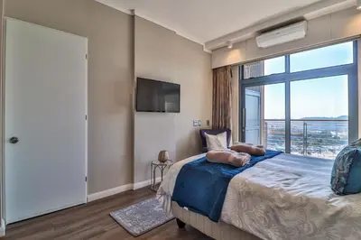 a bedroom with a large bed with a large window at Menlyn Maine Unit 1420 in Pretoria