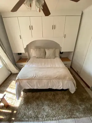 a bedroom with a bed with white cabinets at HomeSweetHome City Apartment in Nelspruit