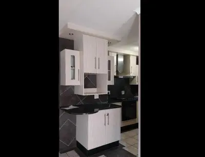a kitchen with white cabinets and black counter tops at HomeSweetHome City Apartment in Nelspruit