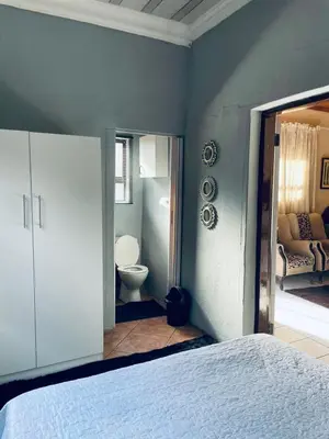 a bedroom with a white bed and a bathroom at Mighty7 Bed and Breakfast Guesthouse in Pretoria