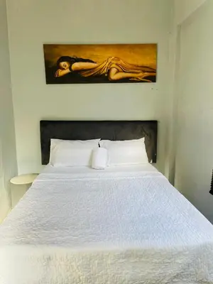 a bedroom with a white bed with a painting on the wall at Mighty7 Bed and Breakfast Guesthouse in Pretoria