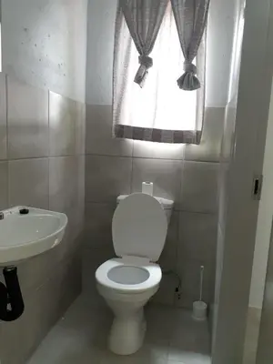 a bathroom with a toilet and a sink and a window at Rethapaki Guesthouse in Secunda