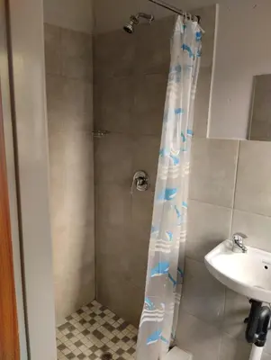 a shower with a white and blue shower curtain next to a sink at Rethapaki Guesthouse in Secunda