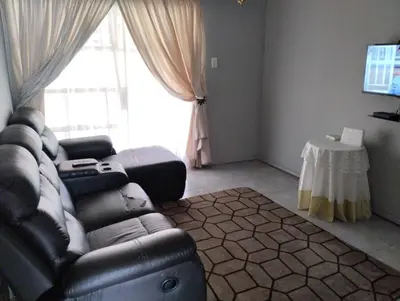 a living room with a leather couch and a large window at Rethapaki Guesthouse in Secunda