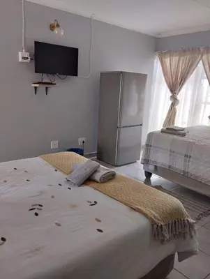 a room with two beds and a television on the wall at Rethapaki Guesthouse in Secunda