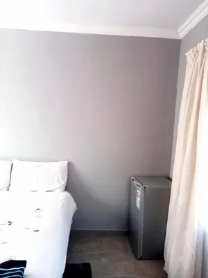 a corner of a room with a bed and a refrigerator at Rethapaki Guesthouse in Secunda
