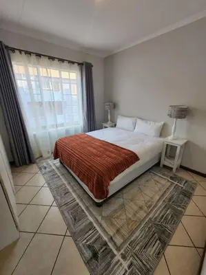 a bedroom with a large bed and a window at 56 - Elegant 2 bed apartment next to Gautrain Centurion in Centurion