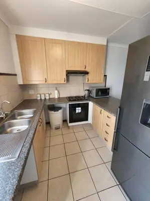 a kitchen with wooden cabinets and a stainless steel refrigerator at 56 - Elegant 2 bed apartment next to Gautrain Centurion in Centurion