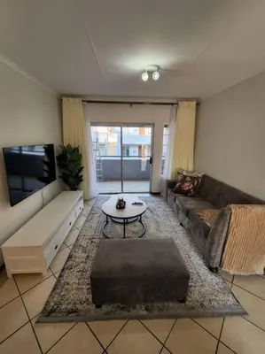 a living room with a couch and a tv at 56 - Elegant 2 bed apartment next to Gautrain Centurion in Centurion