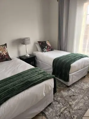 a bedroom with two beds and a lamp on a table at 56 - Elegant 2 bed apartment next to Gautrain Centurion in Centurion