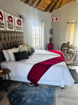 a bedroom with a large bed with a red and white blanket at Banabaka spa and venue in White River