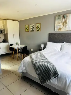 a bedroom with a bed and a table and a kitchen at Banabaka spa and venue in White River