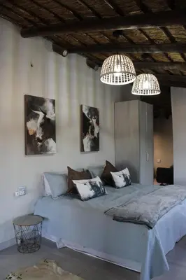 a bedroom with a large blue bed with two chandeliers at Sharon Lodge in Hammanskraal