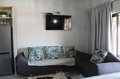 a living room with a couch and a tv on the wall at Sharon Lodge in Hammanskraal