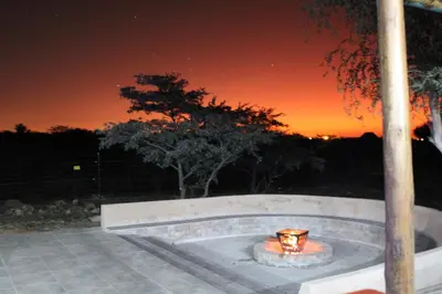 a fire pit at night with a sunset in the background at Sharon Lodge in Hammanskraal