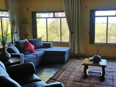 a living room with a couch and two windows at Paradise View Guesthouse in Graskop