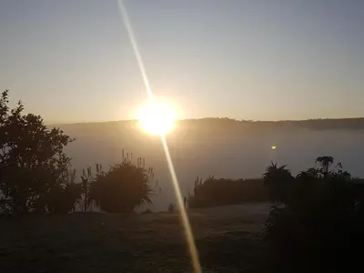 a sun rising over a foggy field with a light pole at Paradise View Guesthouse in Graskop