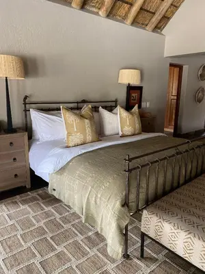a bedroom with a large bed with gold pillows at Simbavati River Sands in Timbavati Game Reserve