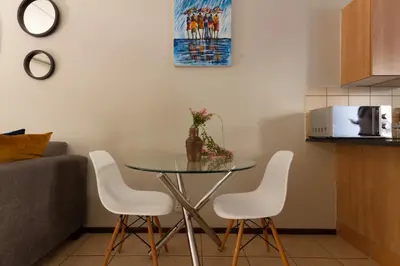 a dining room table with white chairs in a kitchen at 82 NOLE 2bed 2 bath apartment in Midrand