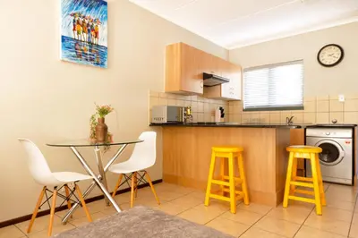 a kitchen with a table and stools in a room at 82 NOLE 2bed 2 bath apartment in Midrand